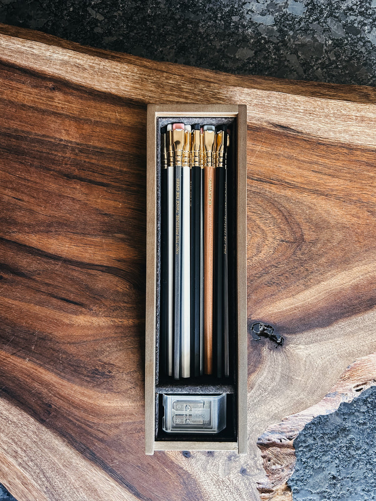 A 12-piece pencil set in an aged pine box with a black cork interior, featuring Matte, 602, Natural, and Pearl pencils, alongside a Grey Two-Step Long Point Sharpener.