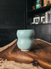 A handmade 'Laos' mug featuring a unique bubbly shape, in a teal color with speckled details and a smooth matte finish.