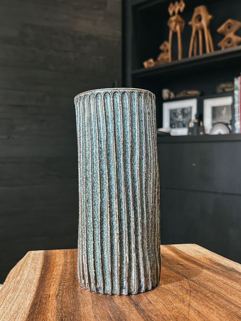 Tall ceramic vase with ribbed texture and dark blue glaze.