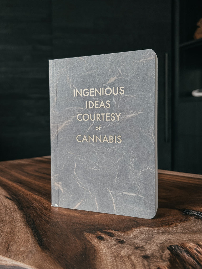 A vintage-inspired journal with gold foil lettering reading “Ingenious Ideas Courtesy of Cannabis,” created by The Mincing Mockingbird.