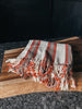A tan and red striped Turkish towel made of soft, lightweight cotton.