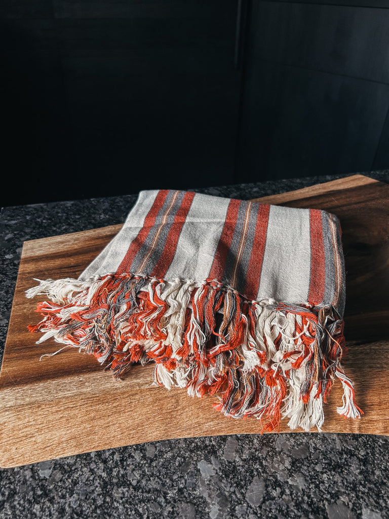 A tan and red striped Turkish towel made of soft, lightweight cotton.
