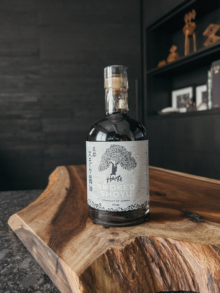 A bottle of Haku Smoked Shoyu, a premium Japanese soy sauce traditionally brewed and cold-smoked with Mizunara oak for a rich, savory flavor.