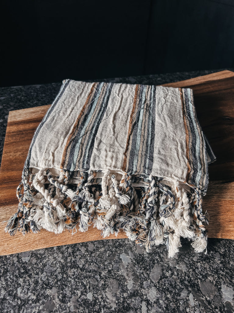 A tan and gray striped Turkish towel made of soft, lightweight cotton.