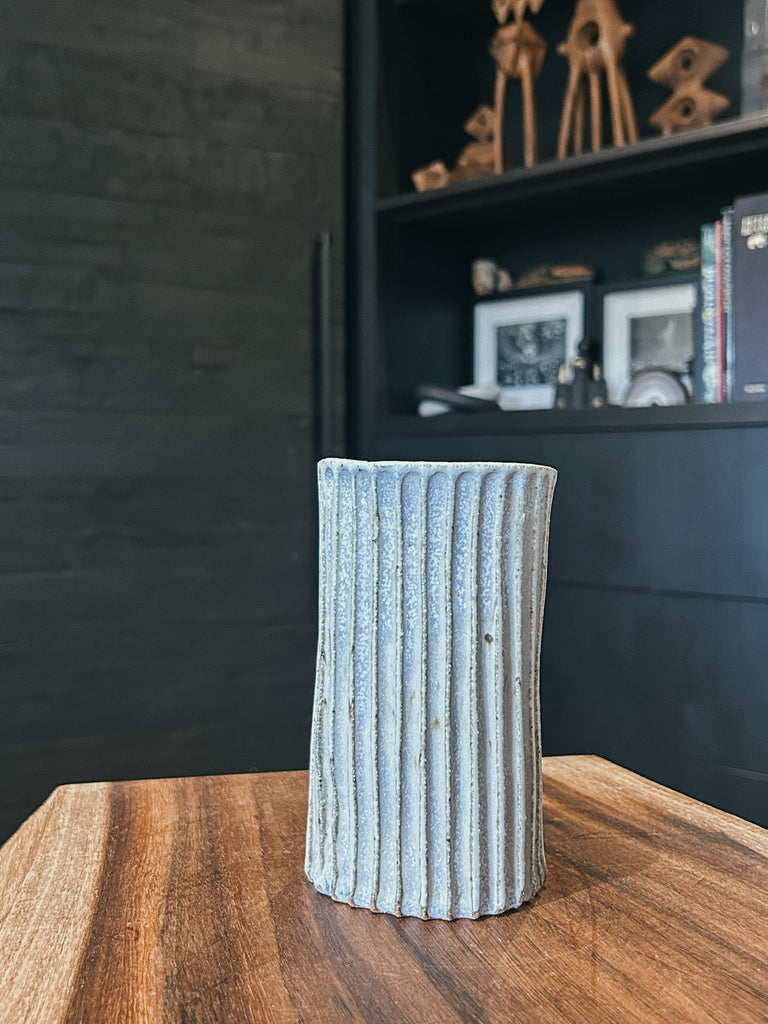 A tall ceramic tumbler with a ribbed texture and lavender glaze.