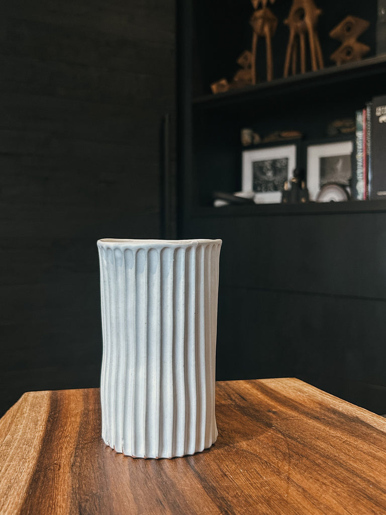 A tall ceramic tumbler with a ribbed texture and white glaze.